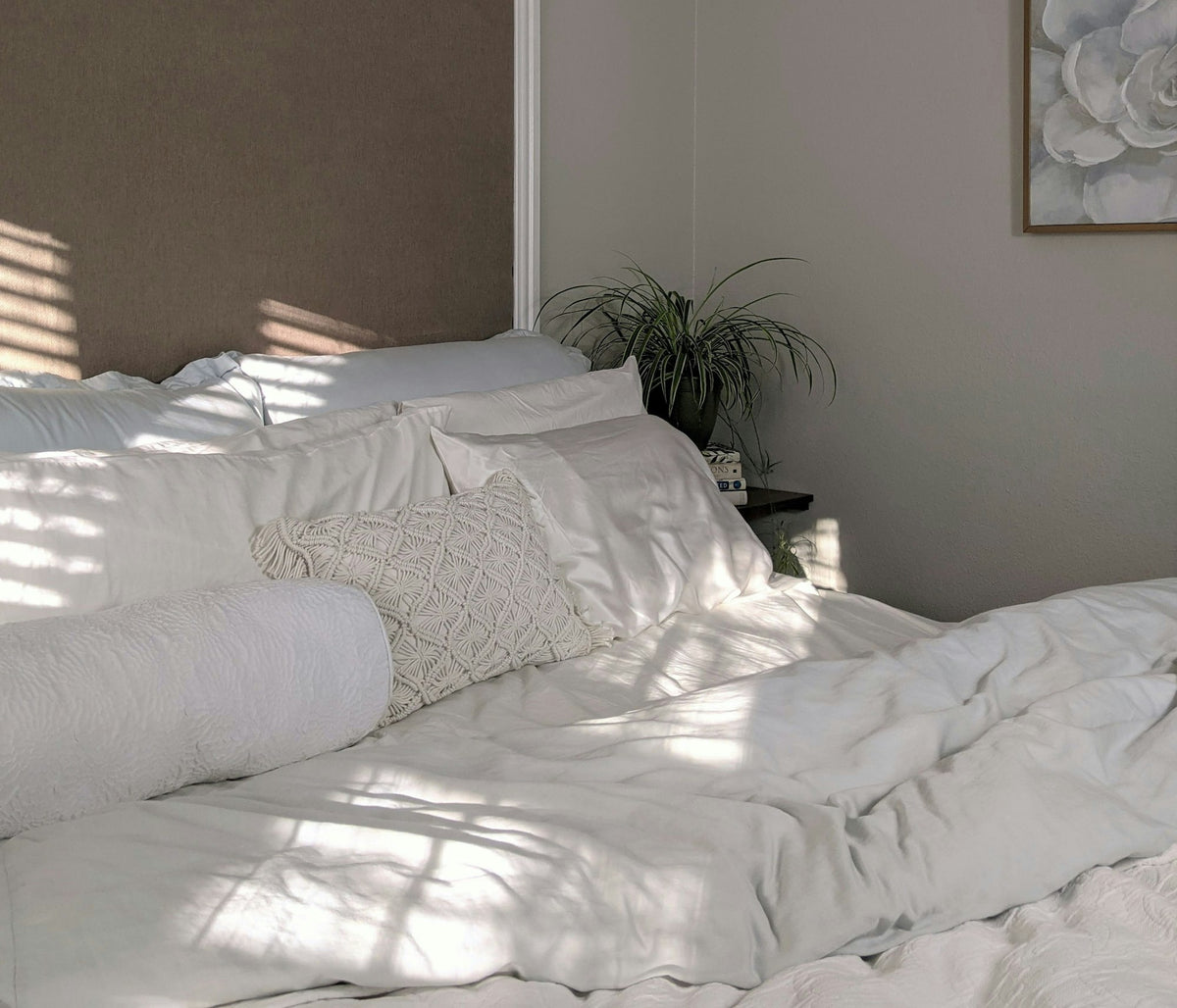 White bed linen next to a plant